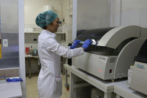 Lab technician checks the samples in biochemical blood analyser Lab technician checks the samples in biochemical blood analyser